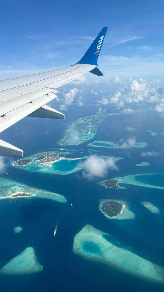 Fly Sydney to Maldives: View from a flight window seat overlooking the turquoise waters of the Maldives. 